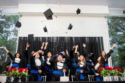 A stage full of graduates throwing their caps in the air.